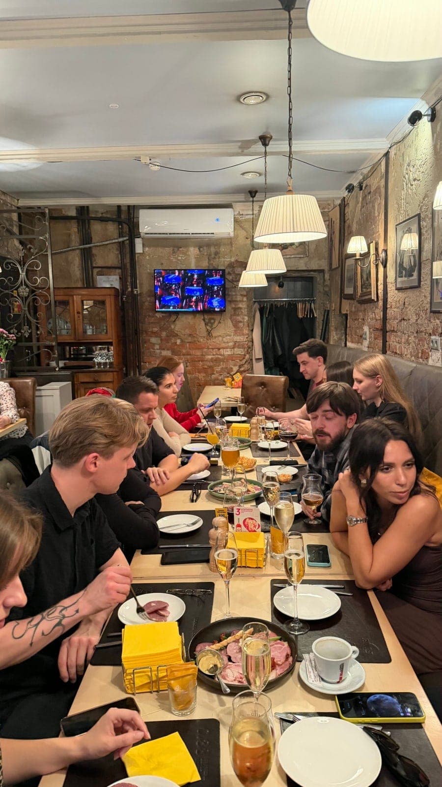 The whole table at Brasserie 0,33: guests talking down a long row of plates and glasses