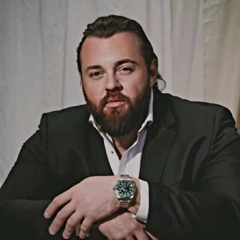 Vlad Falfouchinski seated in a dark suit against a white curtain